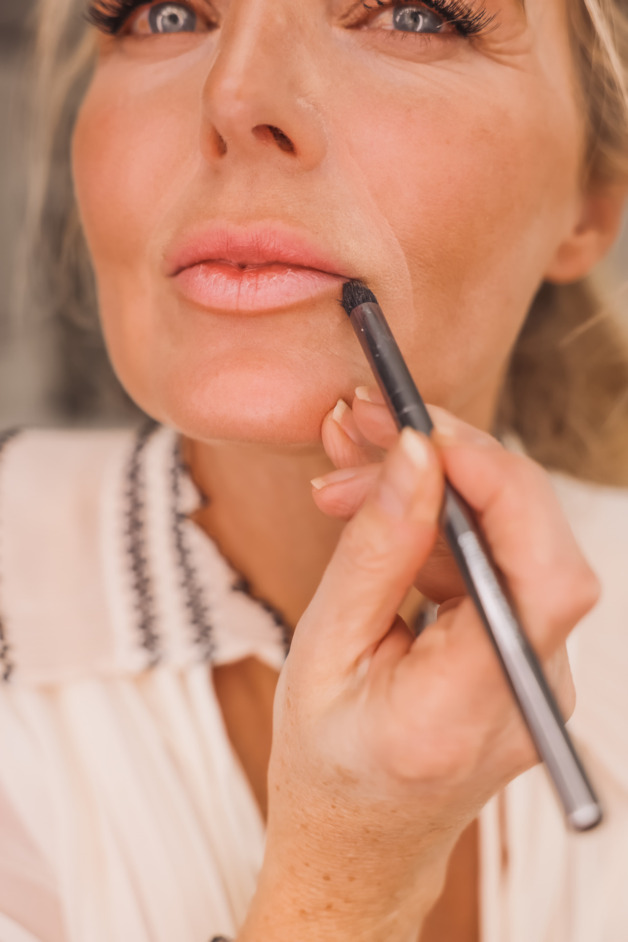 woman using pencil brush one of the makeup brushes you need
